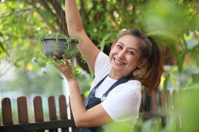 Portrait of a smiling young woman holding plant