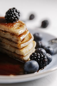 Close up of a fluffy homemade pancakes with syrup and berries