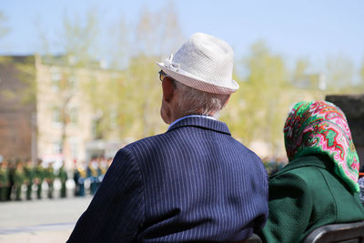 Rear view of man wearing hat sitting outdoors