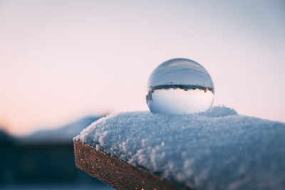 Glass transparent ball in the snow in winter, sun rays reflection. severe frost, cold