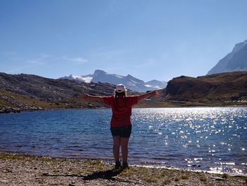 Rear view of woman standing in front of lake