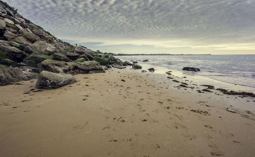 Small wet sand beach surrounded by steep rocks cliffs on the mediterranean sea coastline at sunset