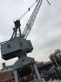 Low angle view of crane against sky in city