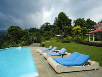 Lounge chairs by swimming pool against sky