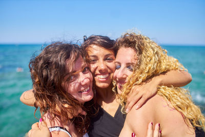 Portrait of happy woman with friends against sea on sunny day