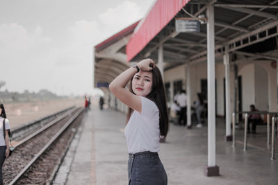 Woman standing at railroad station against sky