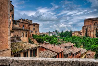 Buildings in town against cloudy sky