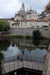 High angle view of man fishing while standing on bridge over lake by church