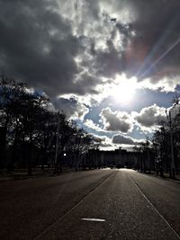 Road by trees against sky in city