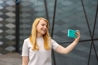 Young blond woman making selfie on smartphone for her followers. young influencer girl
