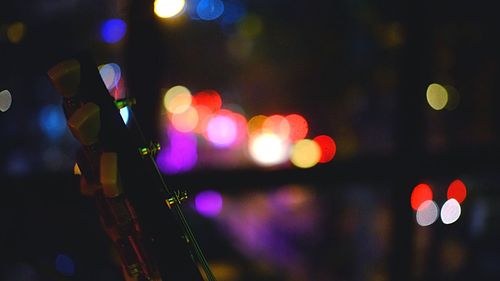 Cropped image of guitar against defocused lights at night