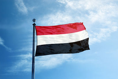 Low angle view of flag against blue sky