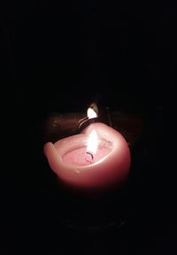 Close-up of lit candle against black background