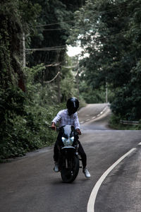 Man riding motor scooter on road