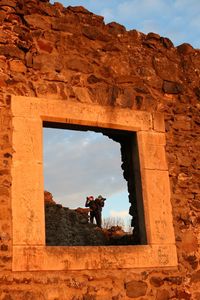 Men photographing ruins of nevytsky castle seen through window