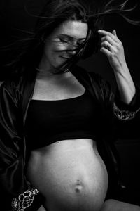 Pregnant woman sitting against black background