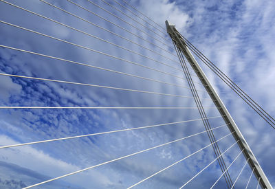 Low angle view of suspension bridge against cloudy sky