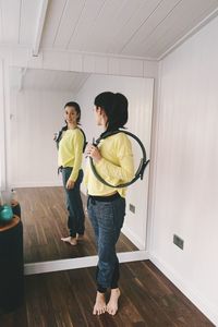 Full length of woman standing in front of a mirror in a pilates studio