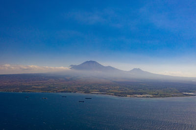 Scenic view of sea and mountains against blue sky