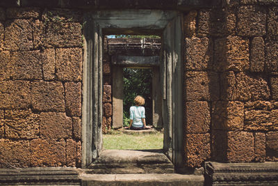 Rear view of woman sitting at historic temple