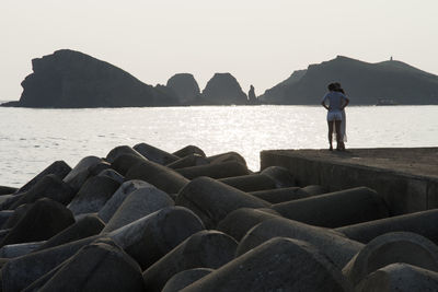 Friends standing on jetty by tetra pods against sea