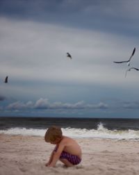 Full length of young woman sitting at beach