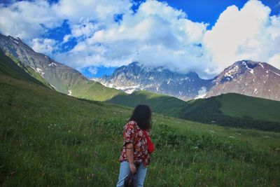 Rear view of woman looking at mountains against sky