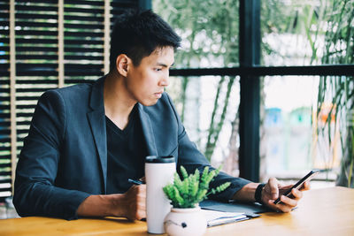 Young man using mobile phone while sitting on table