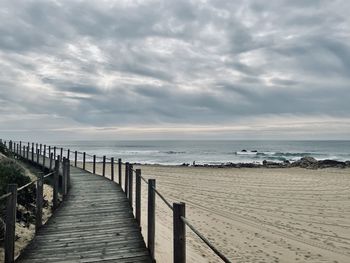 Wooden posts on beach against sky