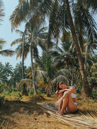 Young woman sitting on palm tree