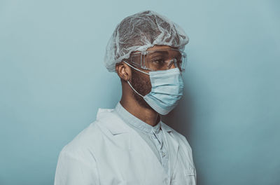 Doctor wearing mask standing against blue background