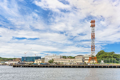 Buildings by river against cloudy sky