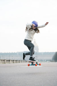 Full length of woman jumping while skateboarding against musee de larmee