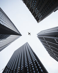 Low angle view of airplane flying over buildings in city