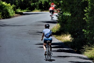 Rear view of woman riding bicycle on road