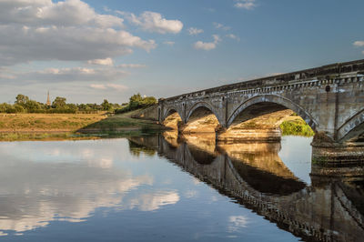 Arch bridge over river against sky
