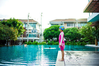 Side view of girl standing by swimming pool