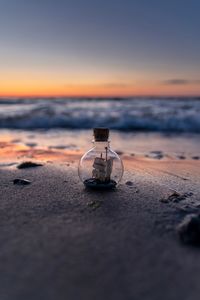 Light bulb at beach against sky during sunset