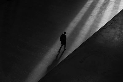 High angle view of silhouette man walking on umbrella