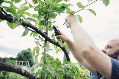 Low angle view of man using mobile phone against sky