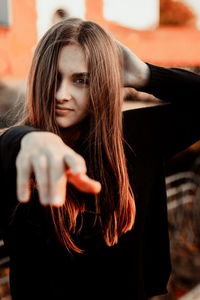 Portrait of beautiful young woman pointing while standing outdoors