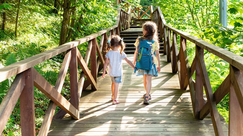 Two girls are heading to the family camp along the tourist hiking route in the mountain forest.