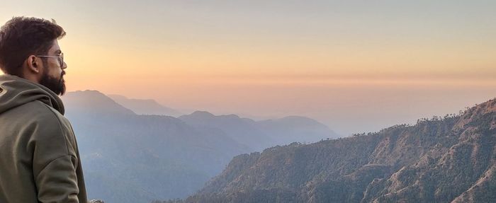 Side view of man standing against mountain during sunset