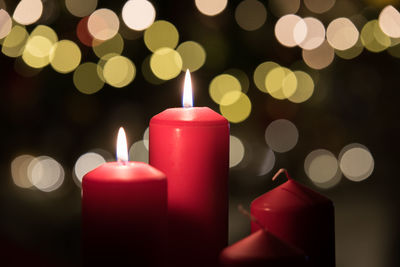 Close-up of illuminated candles against christmas lights