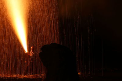 Silhouette man against illuminated fire at night