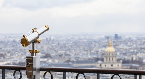 Close-up of coin-operated binoculars against cityscape