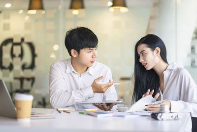 Young colleagues discussing at desk in office