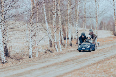 Three happy children playing with big old toy car in countryside, outdoors.