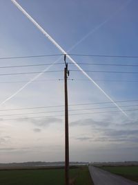 Low angle view of electricity pylon on field against sky