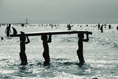 Silhouette people on beach against sky